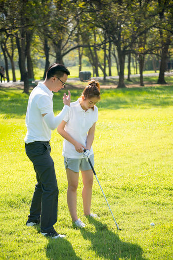 Full length of couple playing golf on field