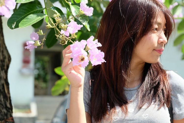Woman looking away by purple flowering plants