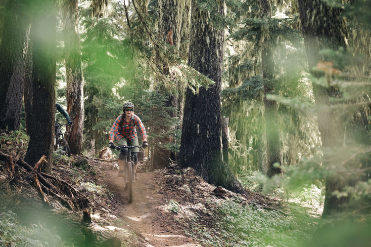 A young woman rides her ike through the forest at mt. hood, oregon.