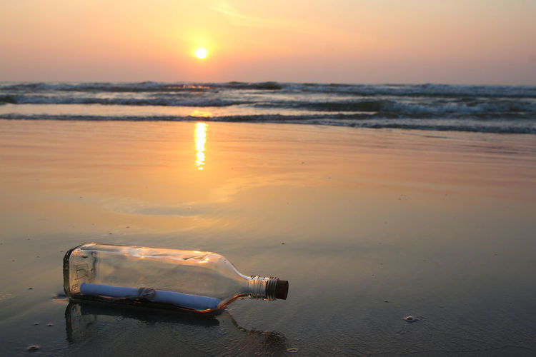 Message in a bottle on beach during sunset