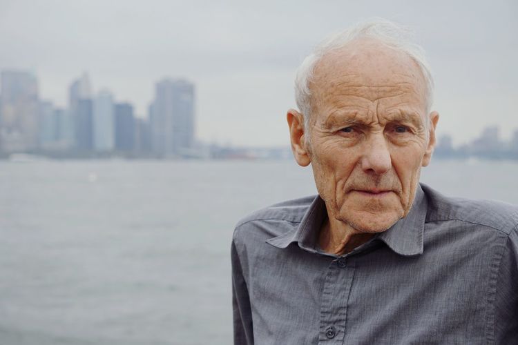 Portrait of senior man in city against sea