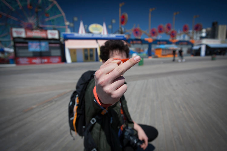 Man showing obscene gesture while standing at coney island