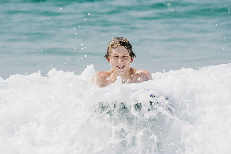 Portrait of smiling shirtless man swimming in sea