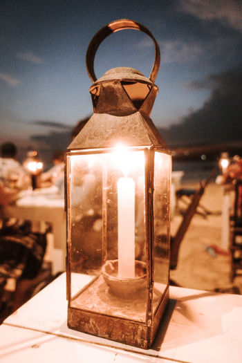 Close-up of illuminated lamp on table against sky