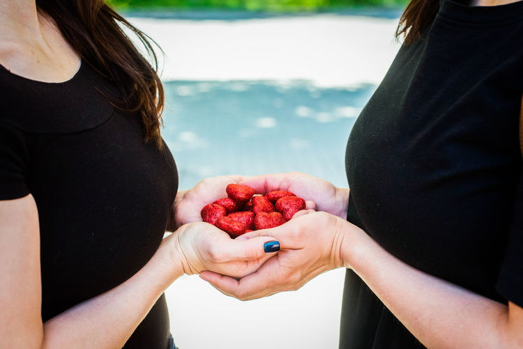 Midsection of woman holding strawberry while standing outdoors