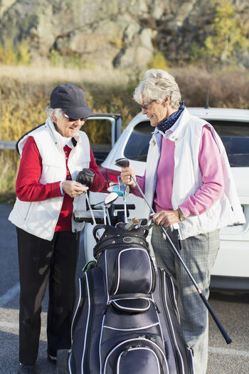 Happy senior women selecting golf clubs from bag