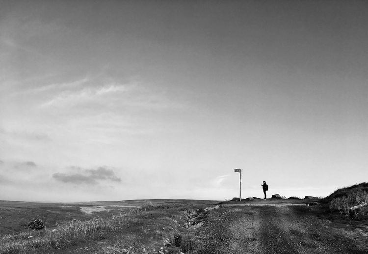 Mid distance view of woman standing on land against sky