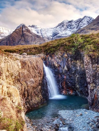 Waterfall and rapids against to scenic snowy mountain landscape, isle of skye, scotland