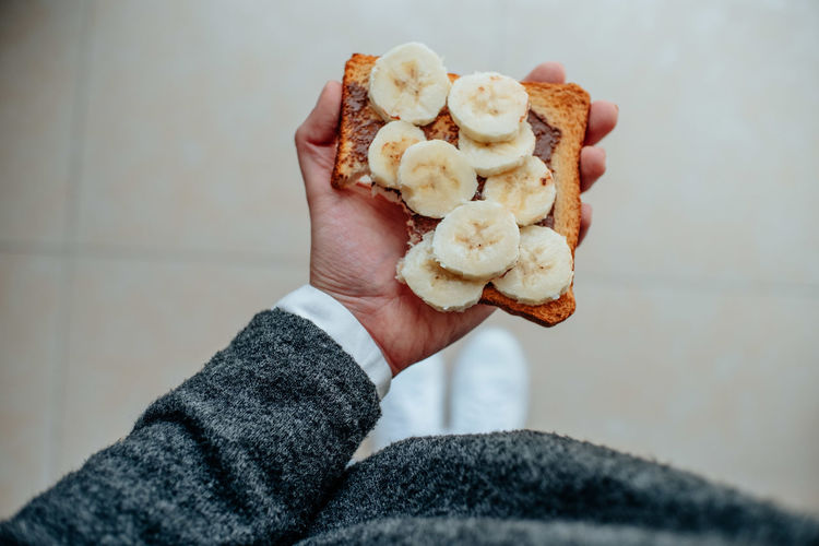 Cropped hand holding bread with banana slices