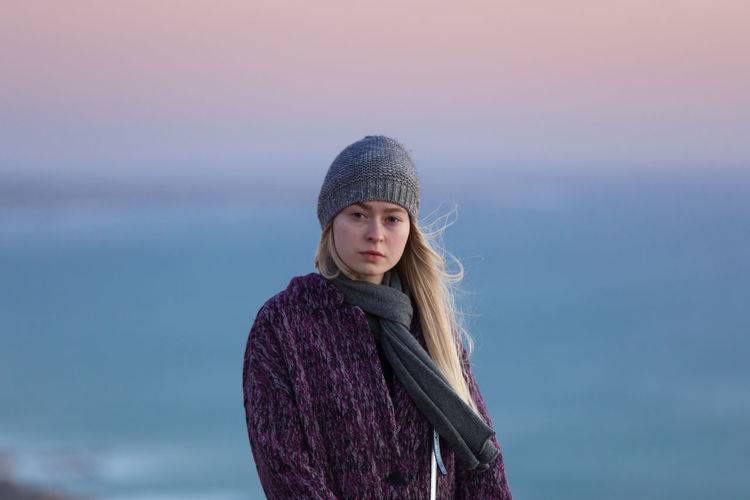 Portrait of teenage girl standing against sea at sunset