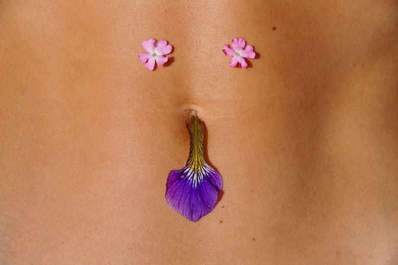 Midsection of woman with flowers on abdomen