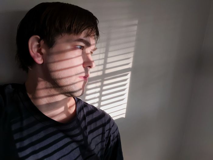 Young man looking away against wall at home