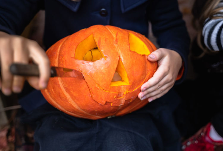 Close-up of man holding pumpkin against orange background
