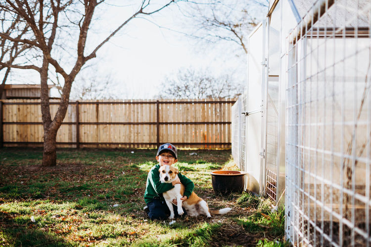 Young boy smiling and hugging dog in backyard during spring