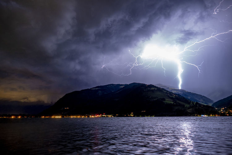 View of lightning over lake and mountains