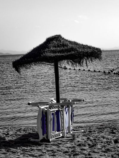 Close-up of deck chairs on beach against sky