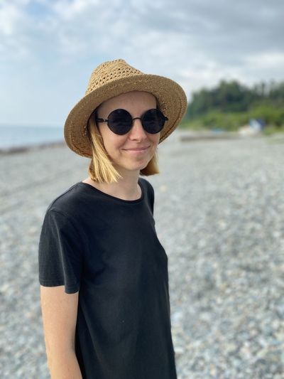 Portrait of mid adult woman wearing sunglasses standing at beach