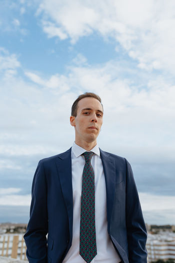 Portrait of businessman standing against sky
