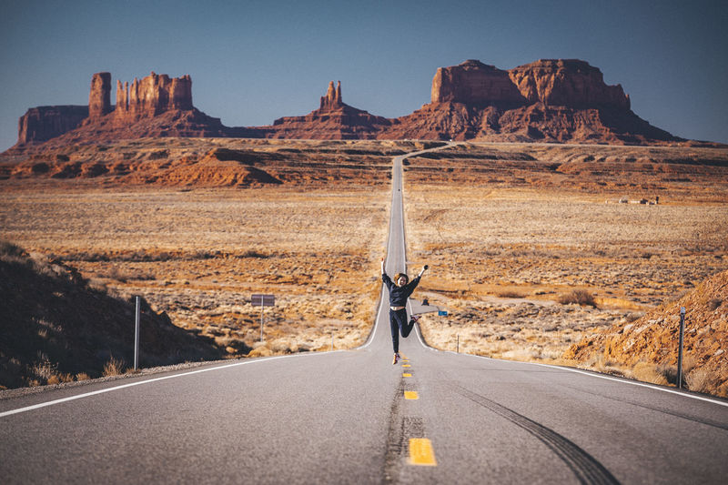 Girl is jumping on the road near forrest gump point, monument valley