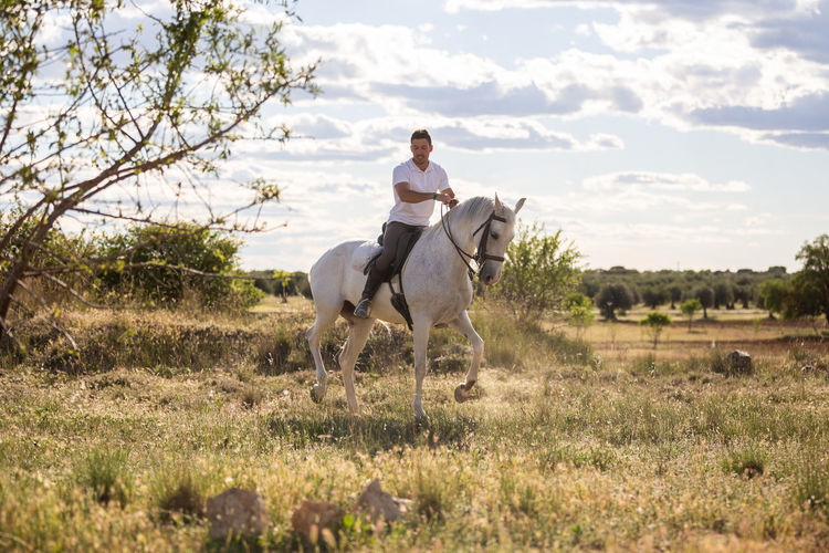 Full length of man riding horse on field