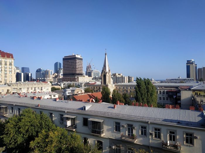 Buildings in city against clear blue sky