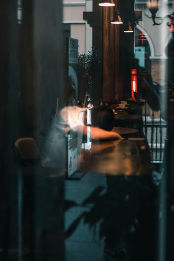 Reflection of man on glass table in restaurant