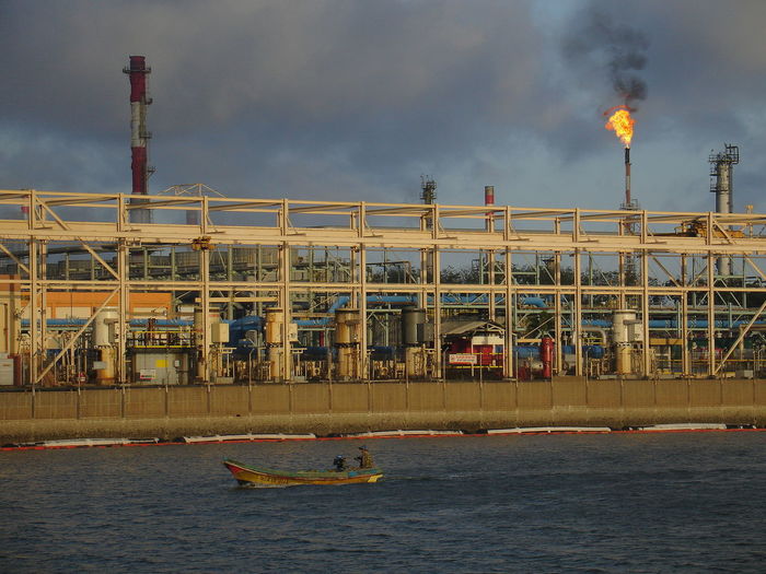 View of factory by sea against sky