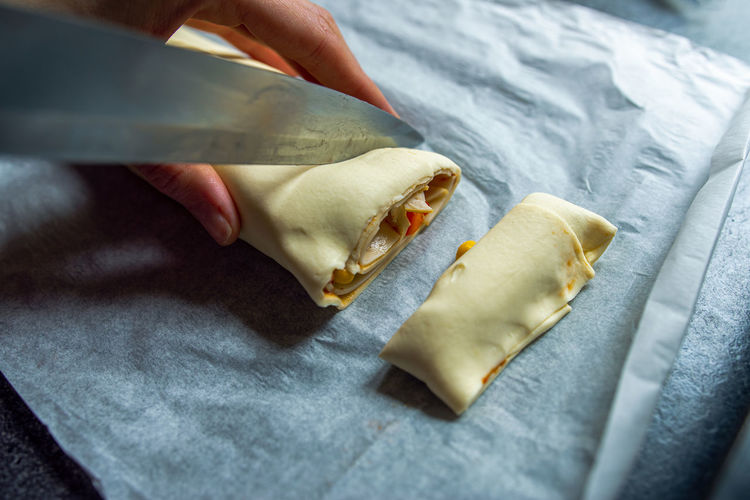 Female hands cut the rolled puff pastry into equal pieces. 