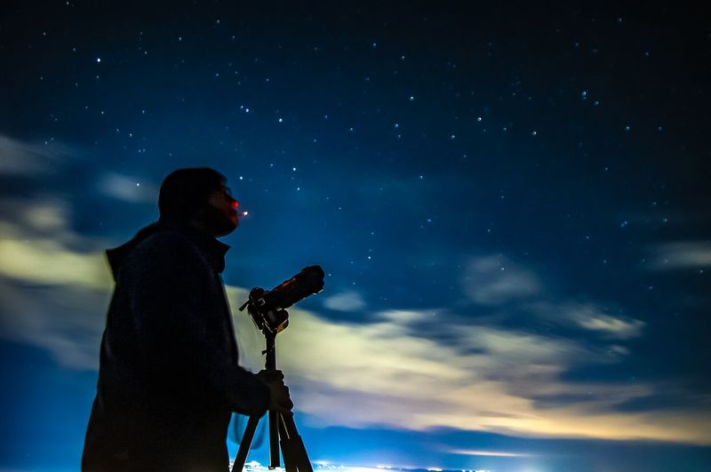 Low angle view of man photographing against sky at night