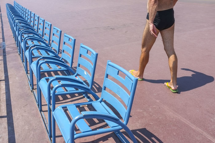 Low section of man walking by blue chairs