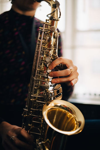 Midsection of woman playing saxophone at studio