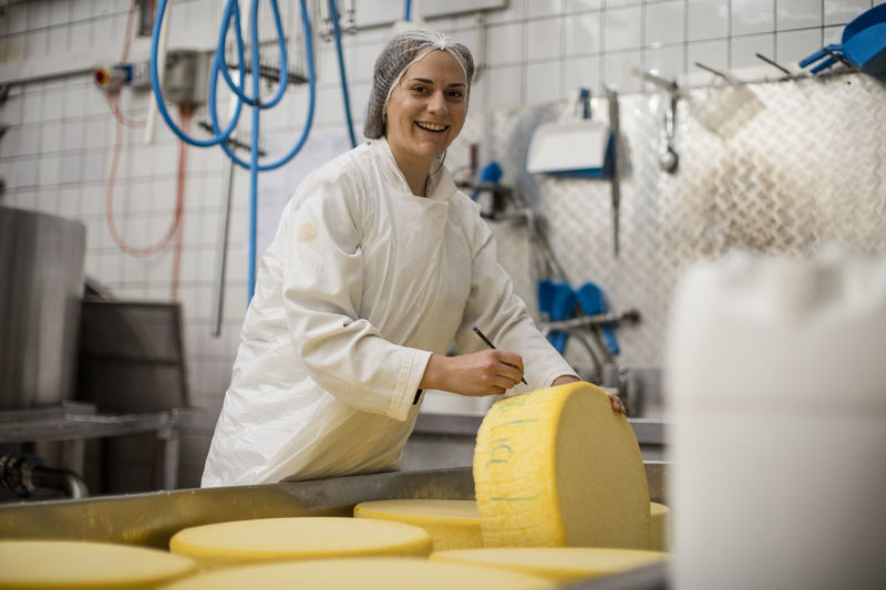 Cheese factory worker labelling cheese wheel