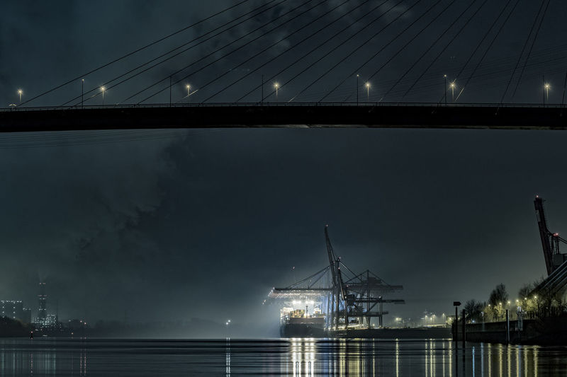 Bridge over river against sky at night