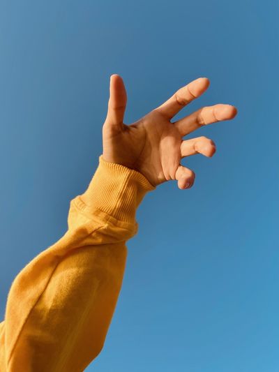 Cropped hand gesturing against blue background