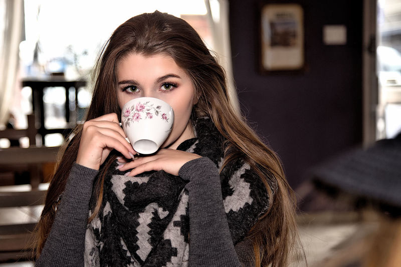 Portrait of young woman drinking coffee in cafe