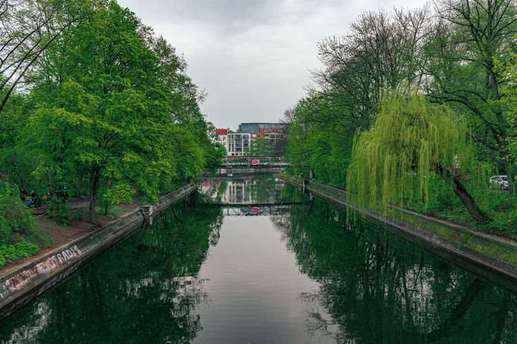 Canal amidst trees against sky