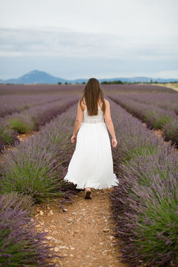 Rear view of woman standing on field against sky