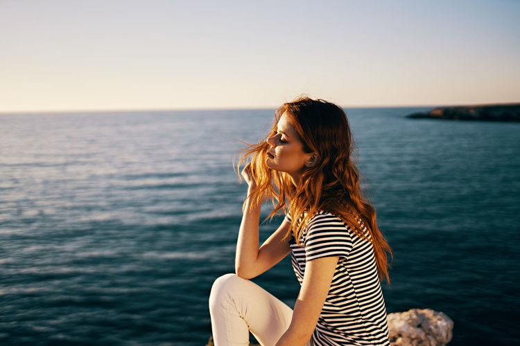 Beautiful young woman in sea against sky