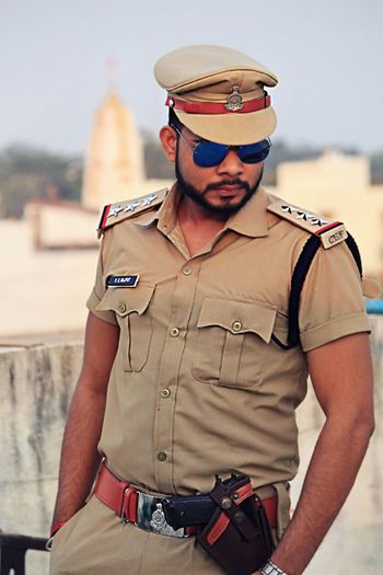 Policeman wearing sunglasses standing against sky