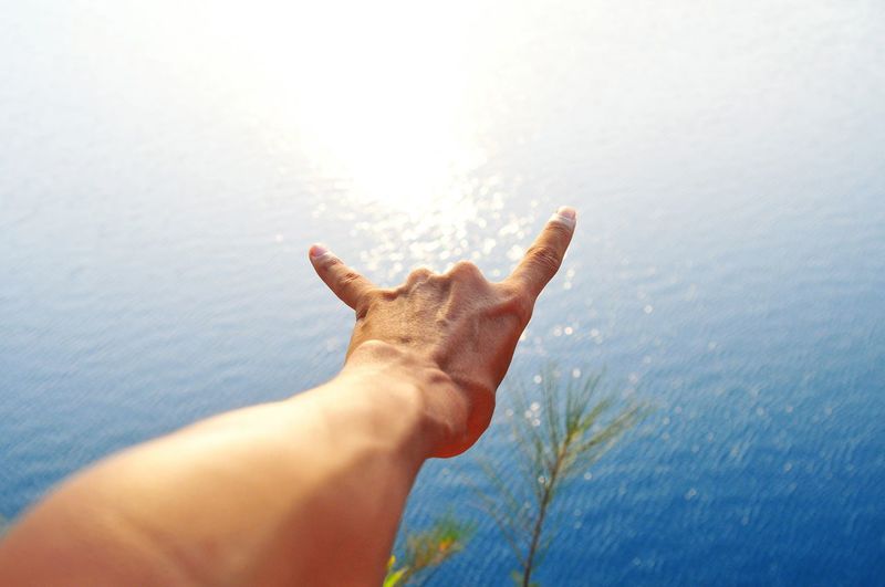 Close-up of person gesturing against lake