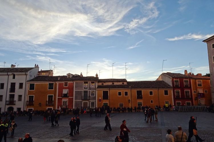 People on street by buildings against sky