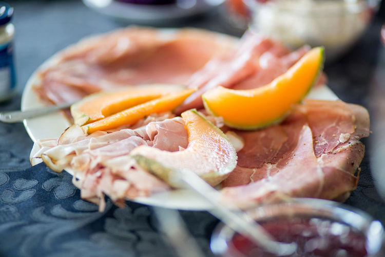 Close-up of sliced muskmelons with cold cuts on table