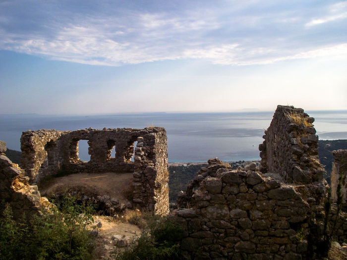Old ruins by sea against sky