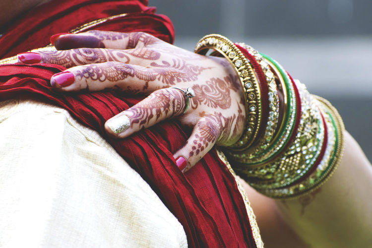 Close-up of woman wearing bangles and henna tattoo with arm around man