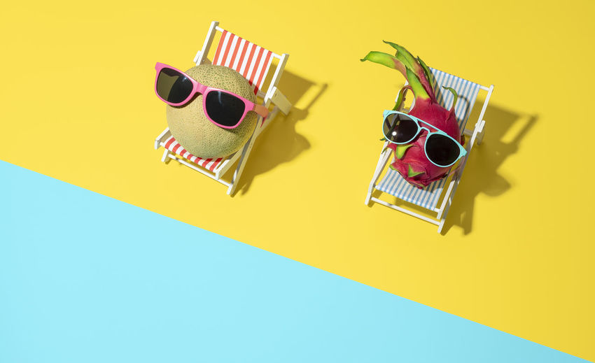 Above view, cantaloupe and dragon fruits in beach chairs. summer concept, exotic fruits  at beach