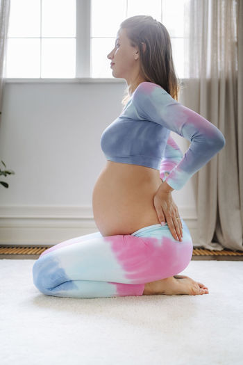 Thoughtful pregnant woman doing yoga at home