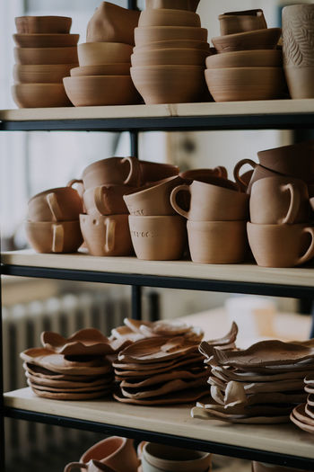 Shelves with ceramic dishware in pottery workshop