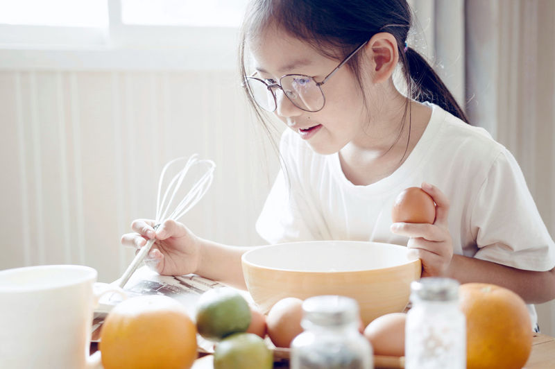 Girl reading book while preparing food at home