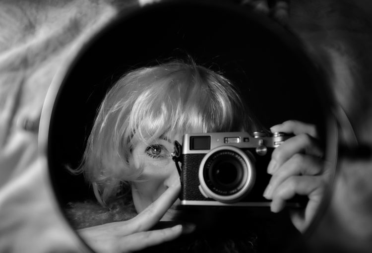 Close-up of young woman self photographing in mirror. 