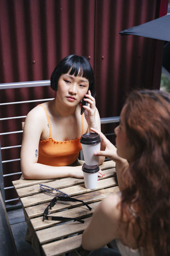 High angle view of lesbian woman talking on phone while sitting at cafe